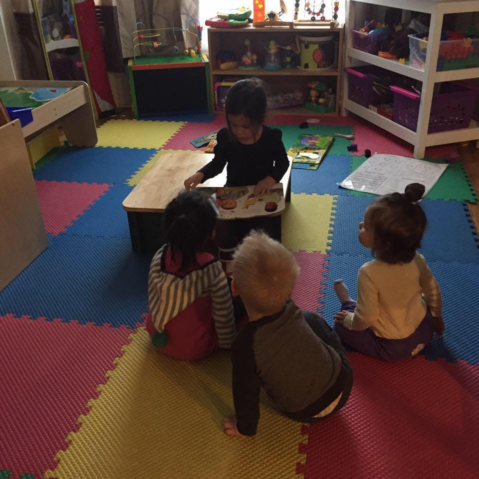 Four children sitting on a colorful mat around a small table