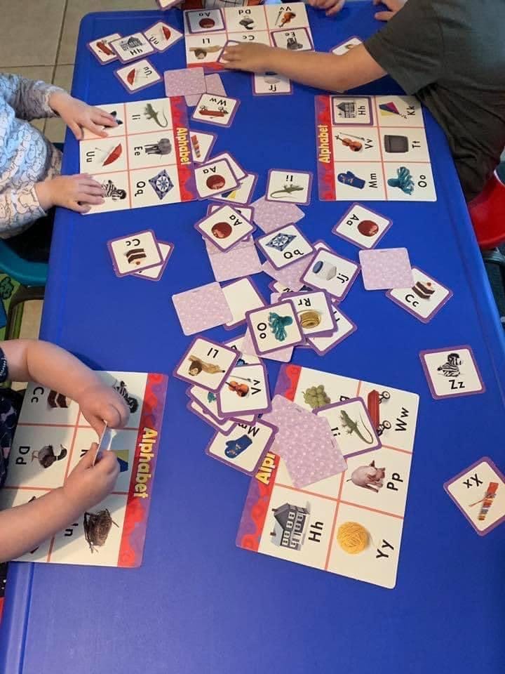Children playing an alphabet matching game at a blue table