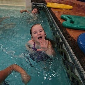 Child in a swimming pool waving