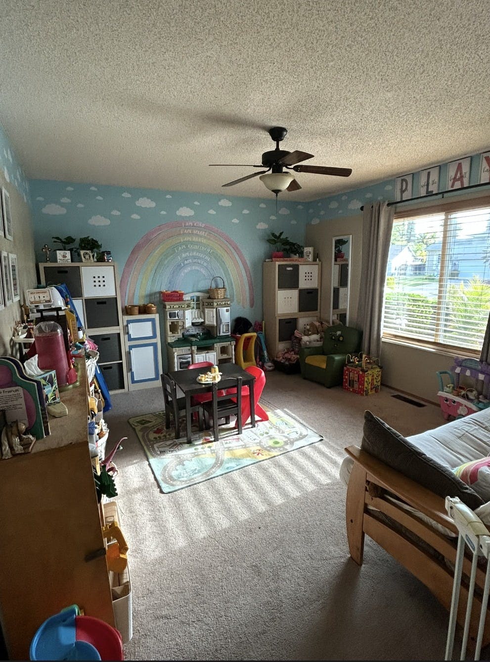 Child's playroom with a rainbow mural, play kitchen, and small table and chairs
