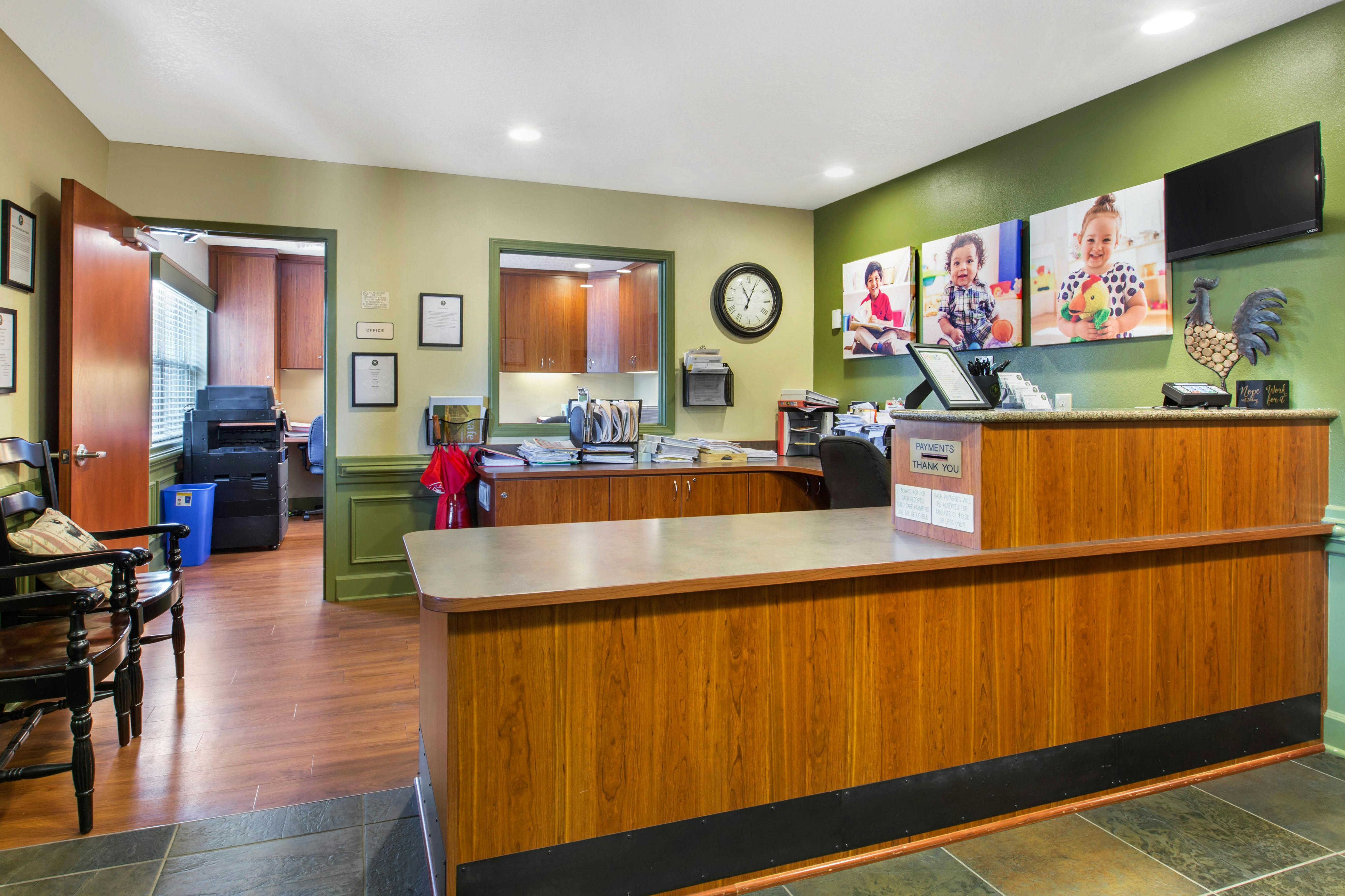 Reception desk with office door, chairs, and pictures of children on the wall