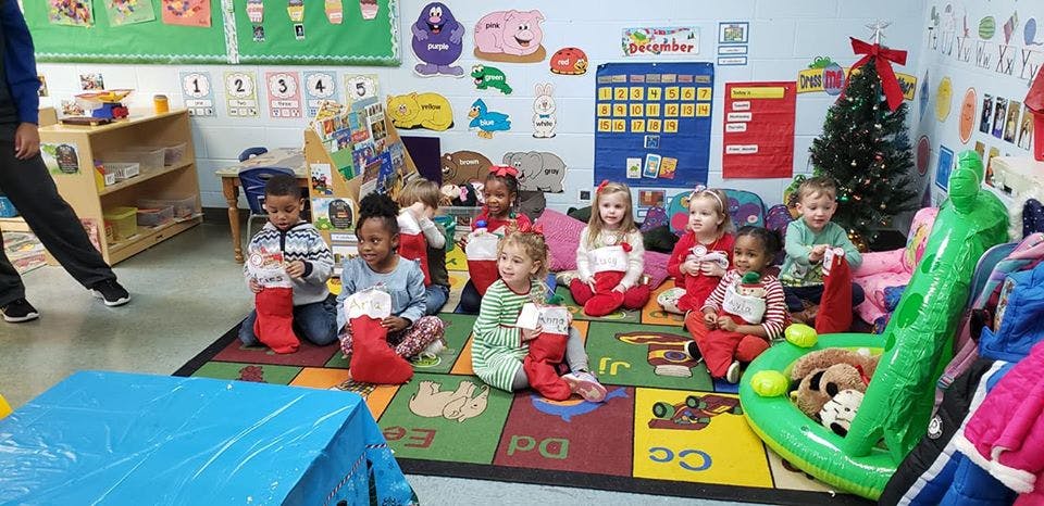 Children sitting on a rug with Christmas stockings in a classroom