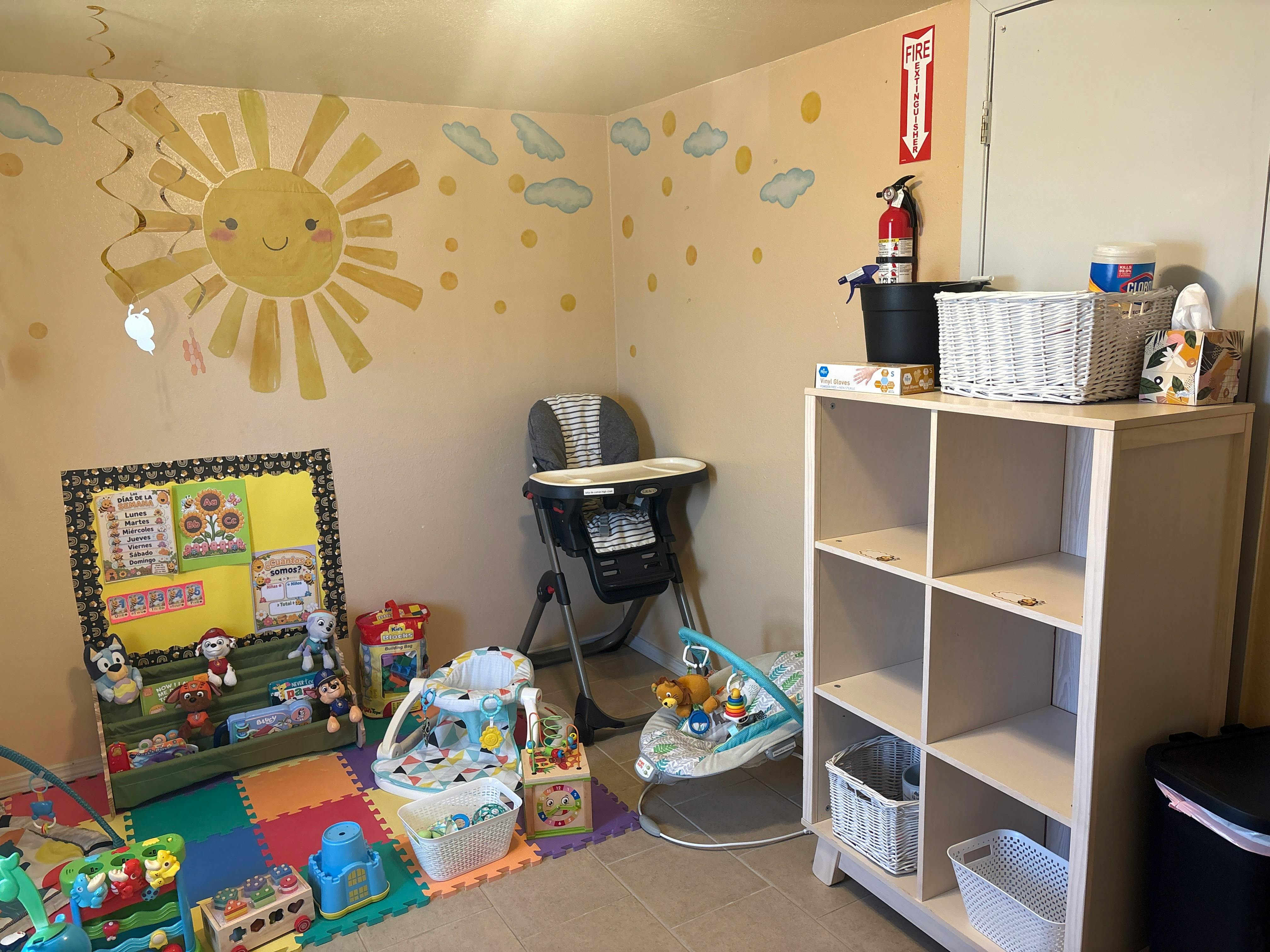 Child care room with toys, high chair, and wall art