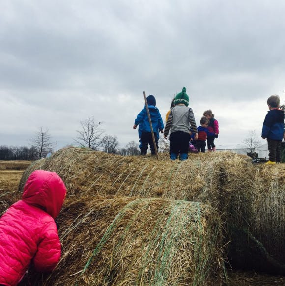 Children playing on hay bales outdoors