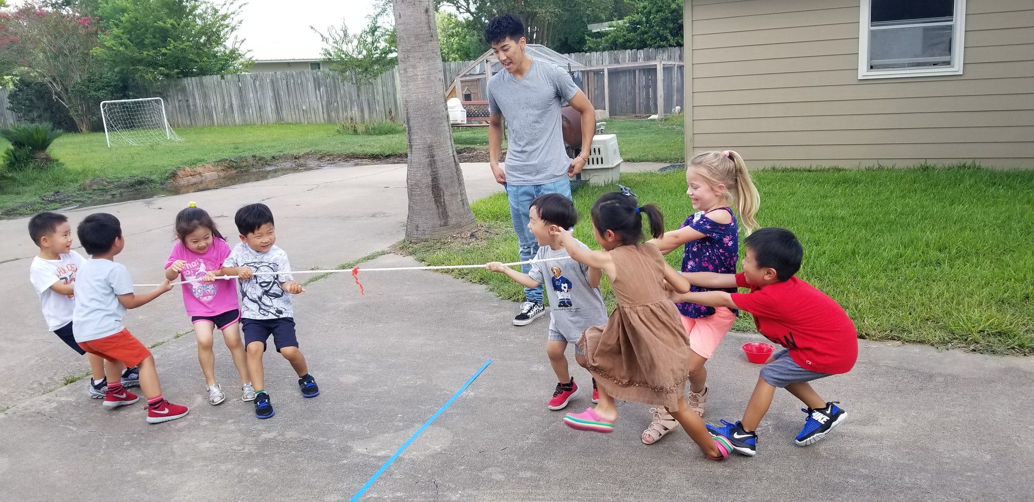 Children playing tug-of-war with an adult supervising