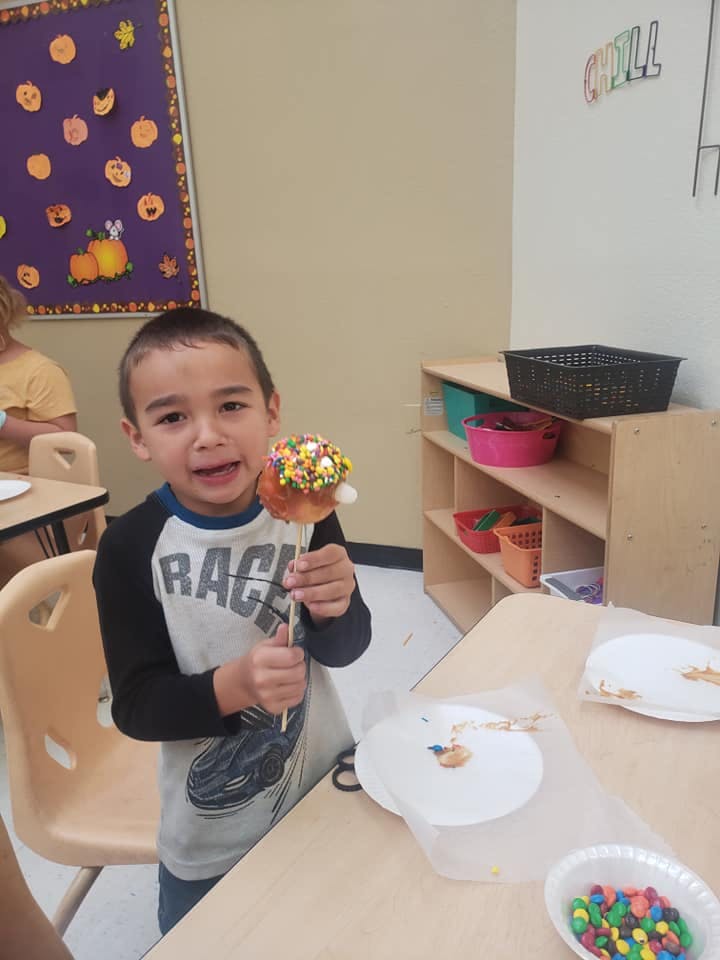 Child holding a caramel apple with sprinkles