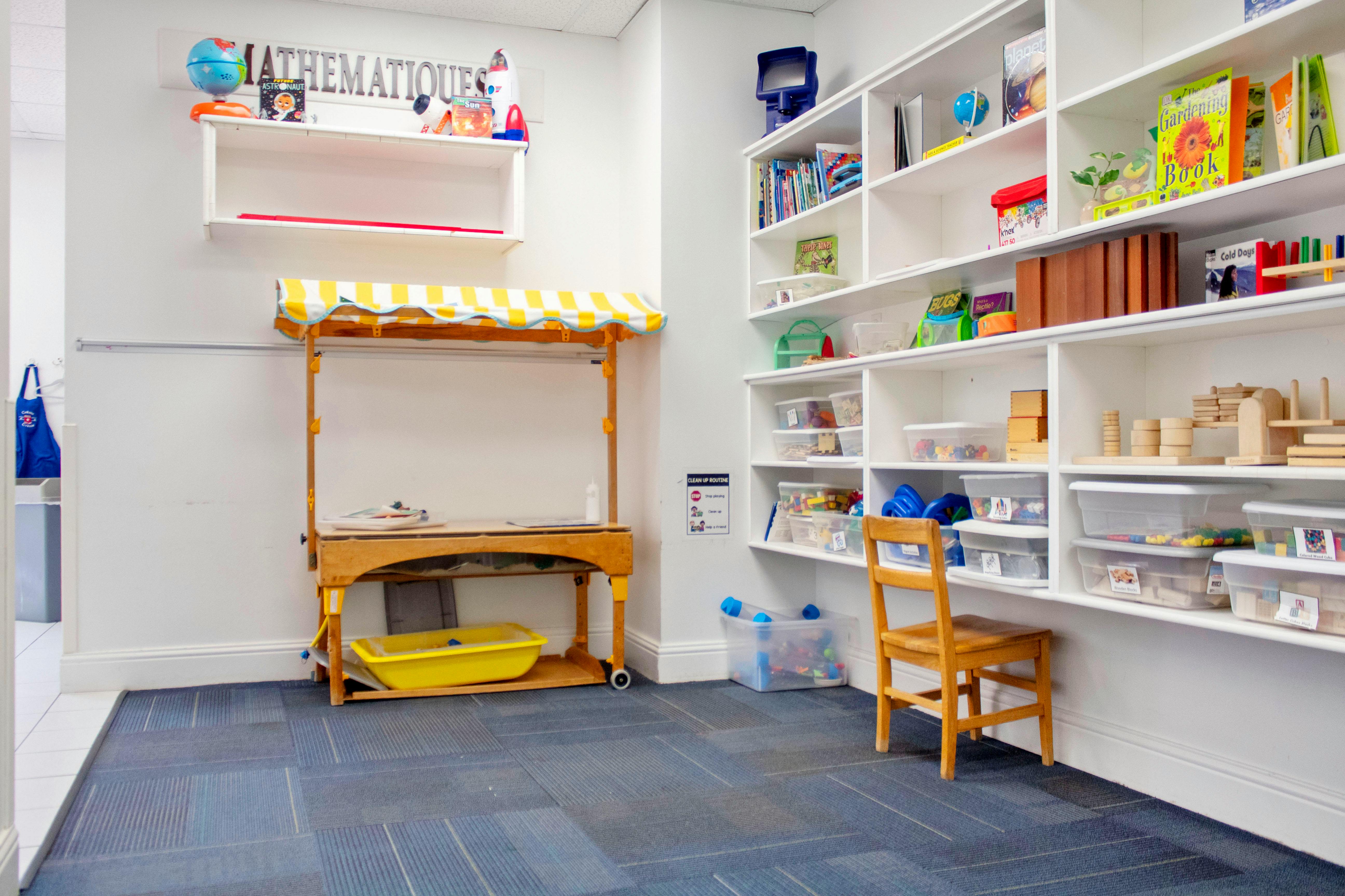 Children's classroom with toy stall, white shelves, and blue carpet