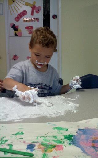 Child playing with white foam on a table