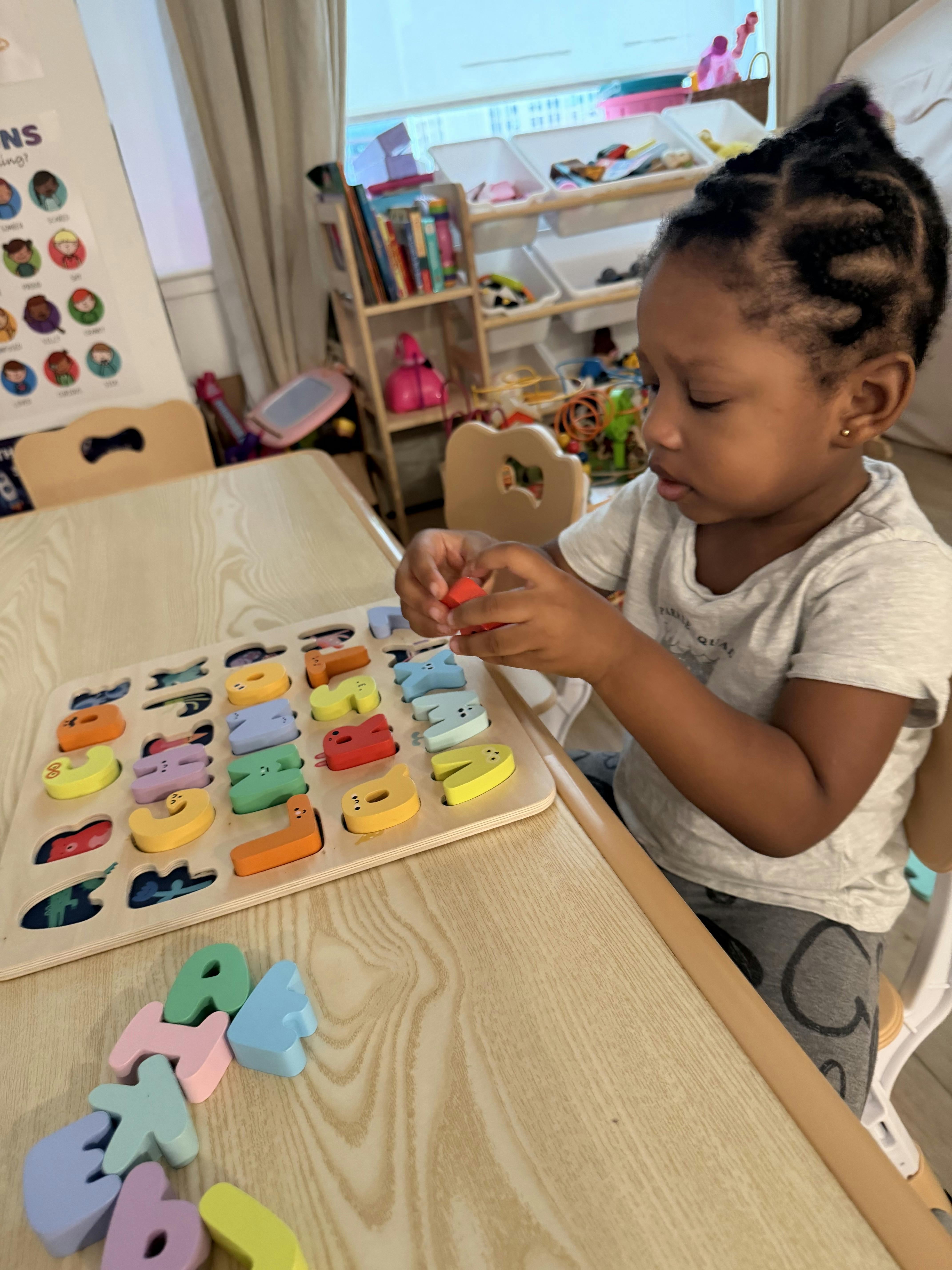 Child playing with a wooden alphabet puzzle at a table