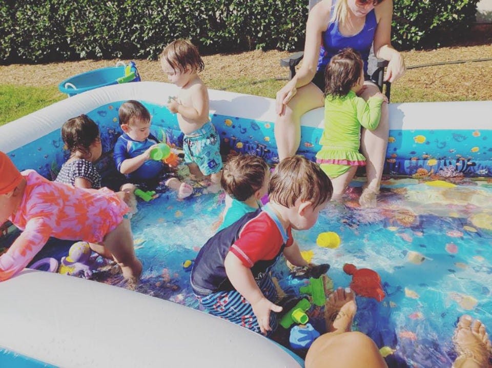 Adult and multiple children playing in an inflatable pool