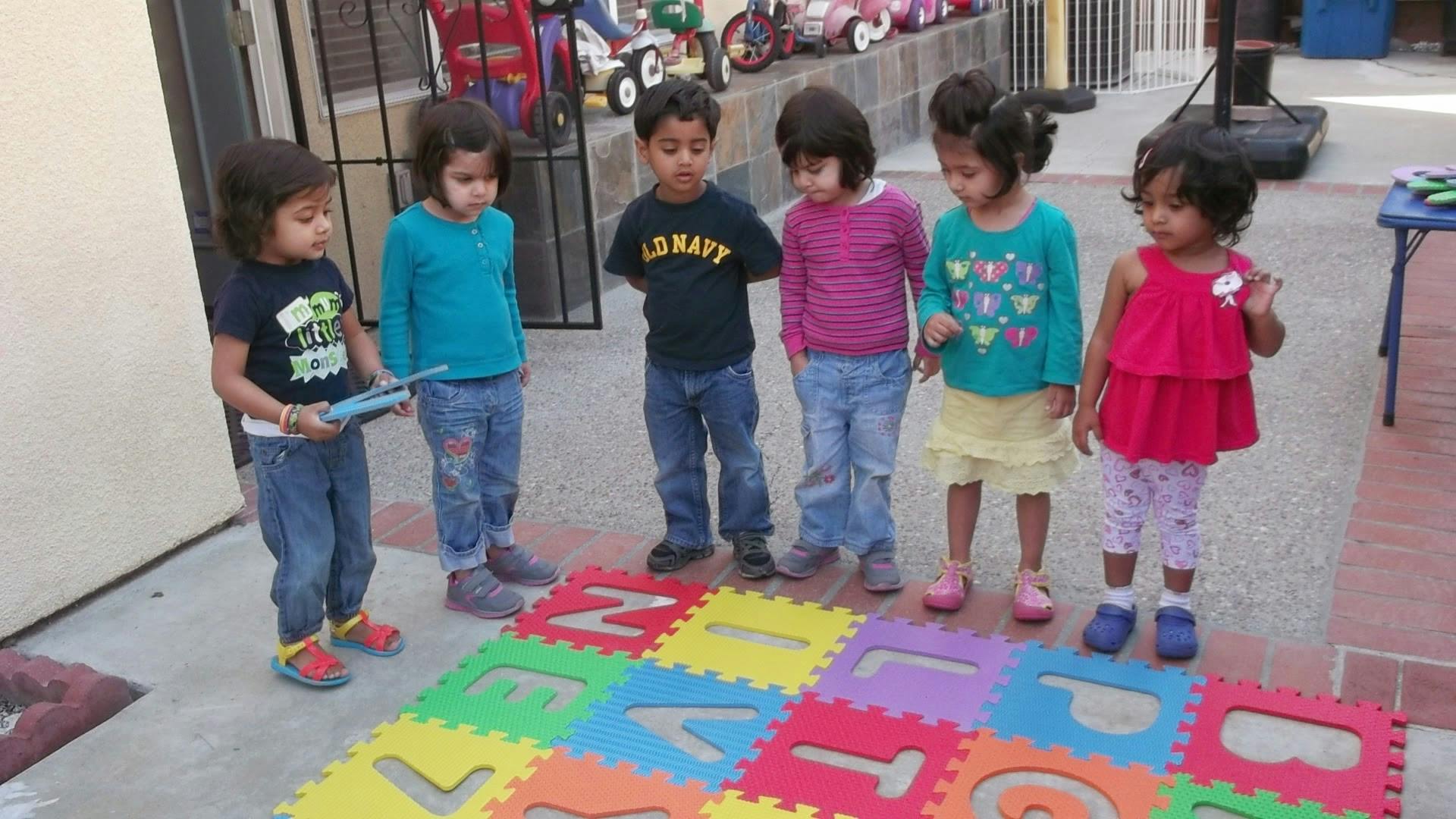 Group of children standing around colorful alphabet floor mats