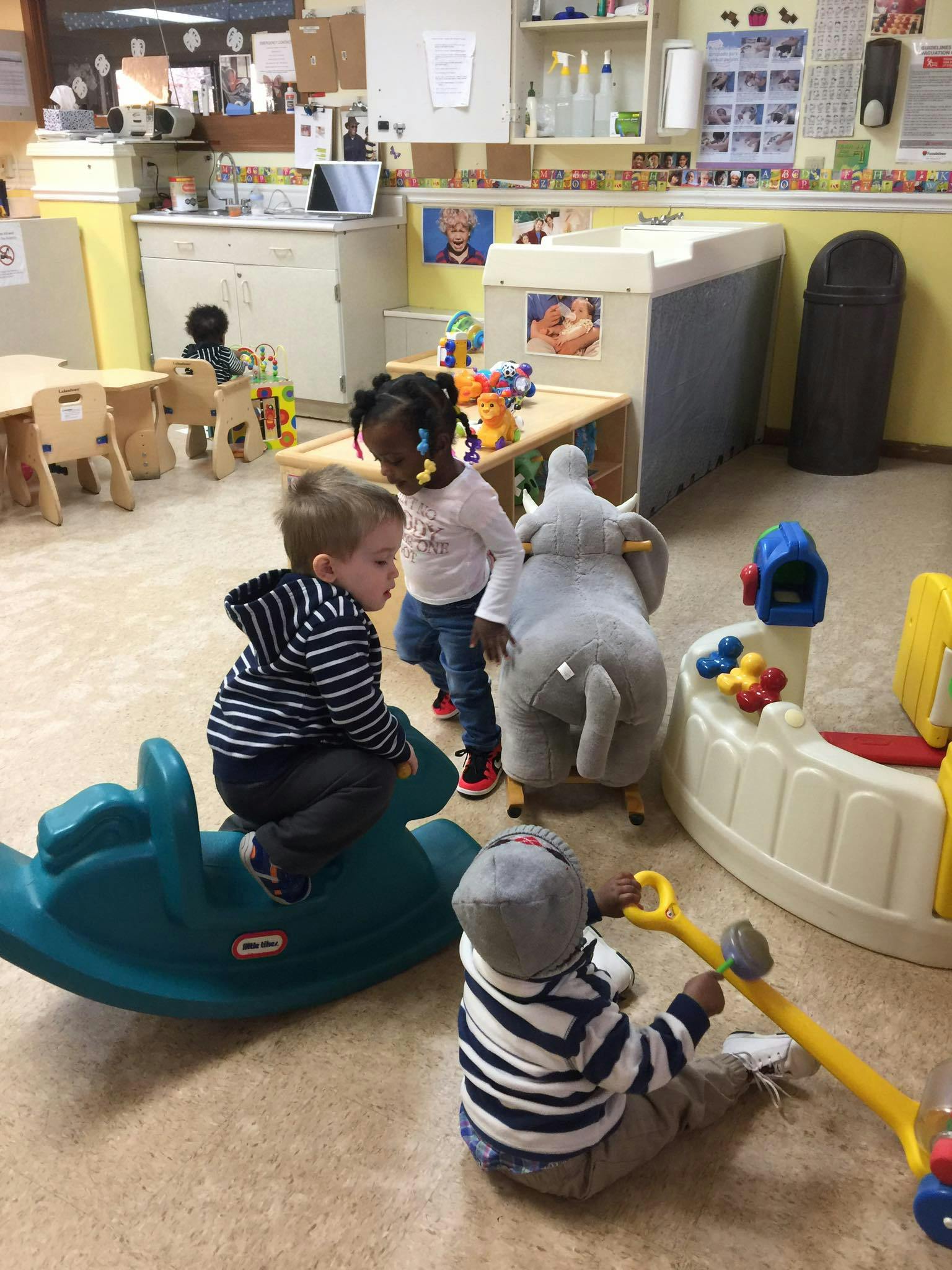 Three children playing with toys in a classroom