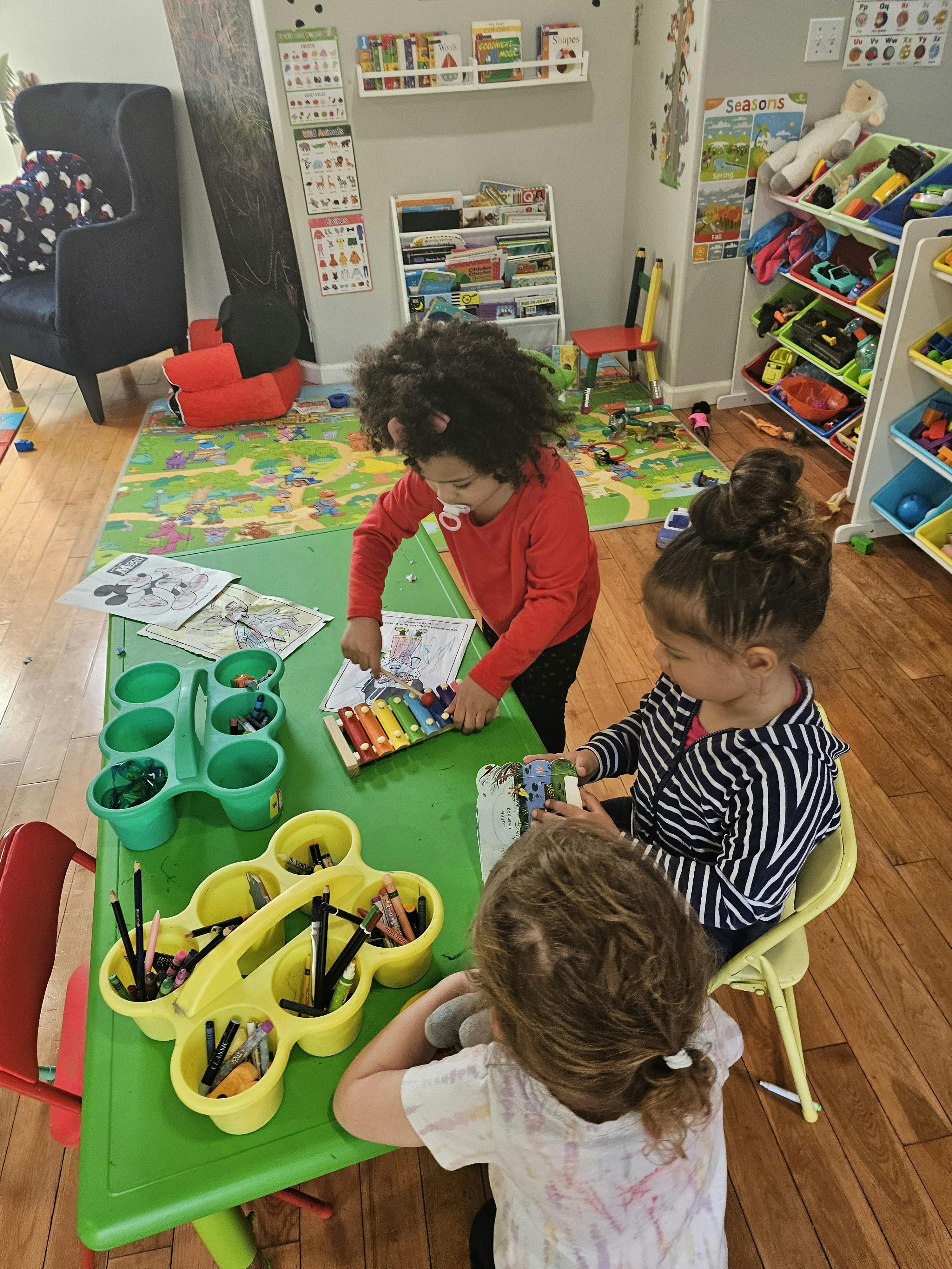 Three children playing with toys at a green table