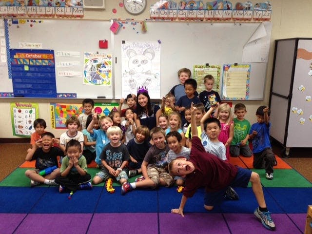 Group of children and one adult posing in a classroom