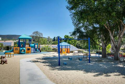 Playground with blue and yellow play structure and swings