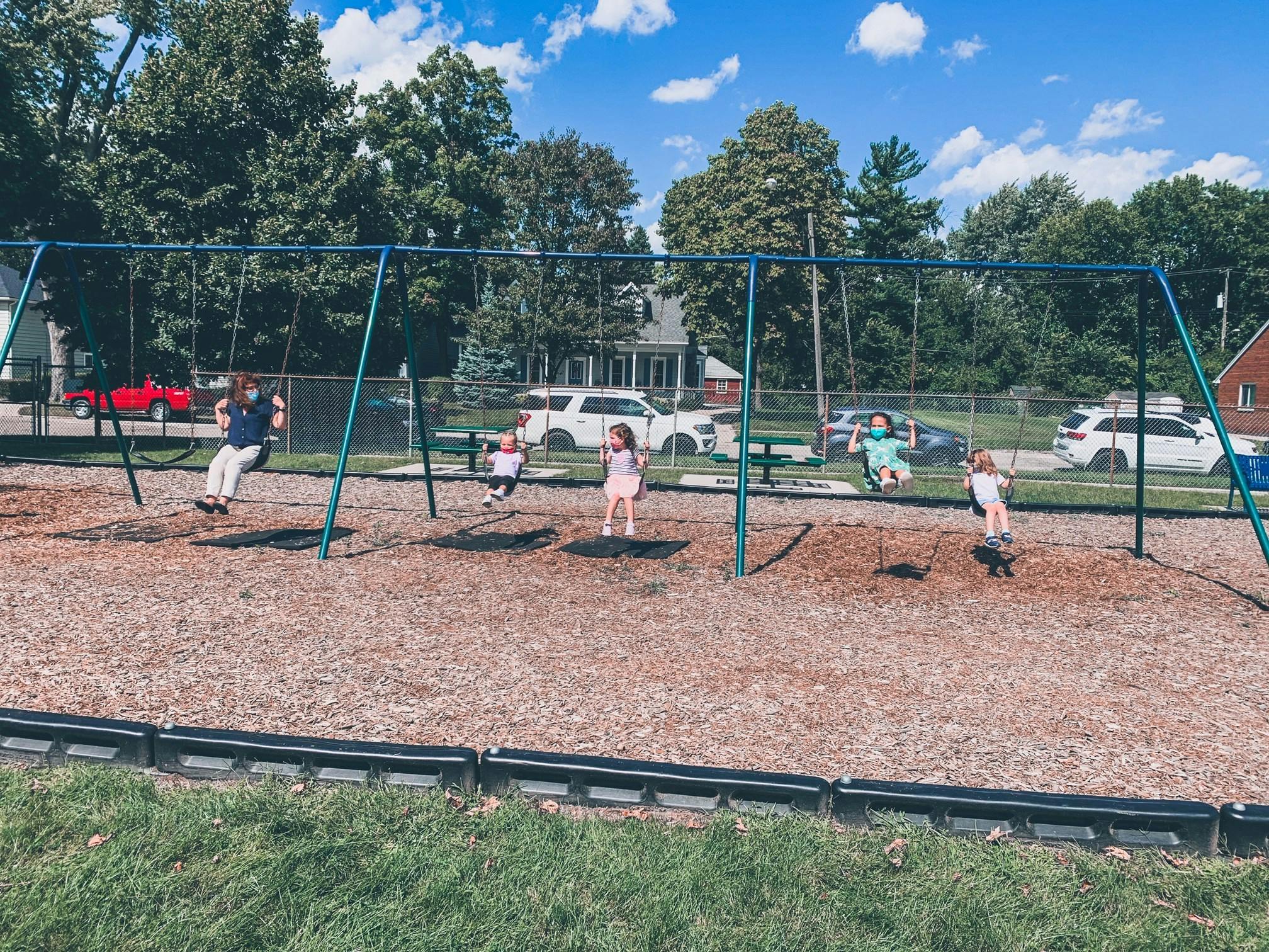 People and children on swings at a playground