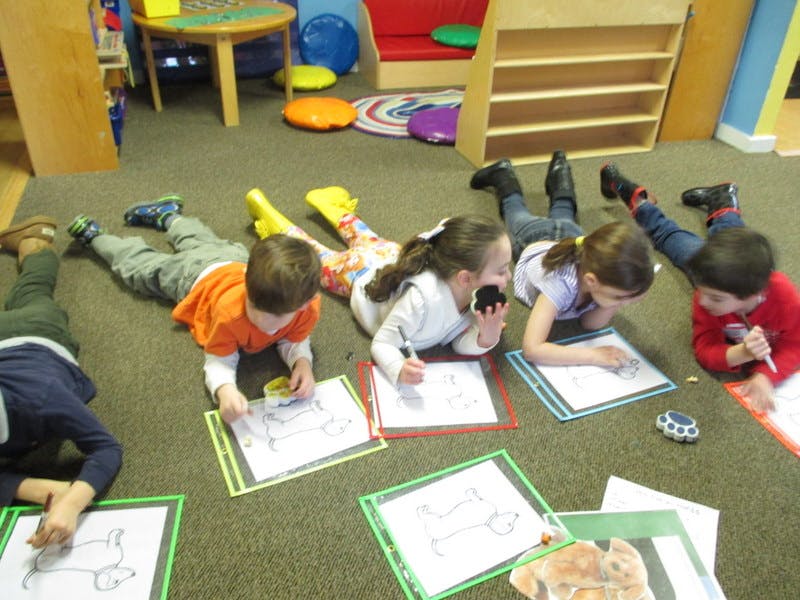 Children lying on the floor drawing on paper
