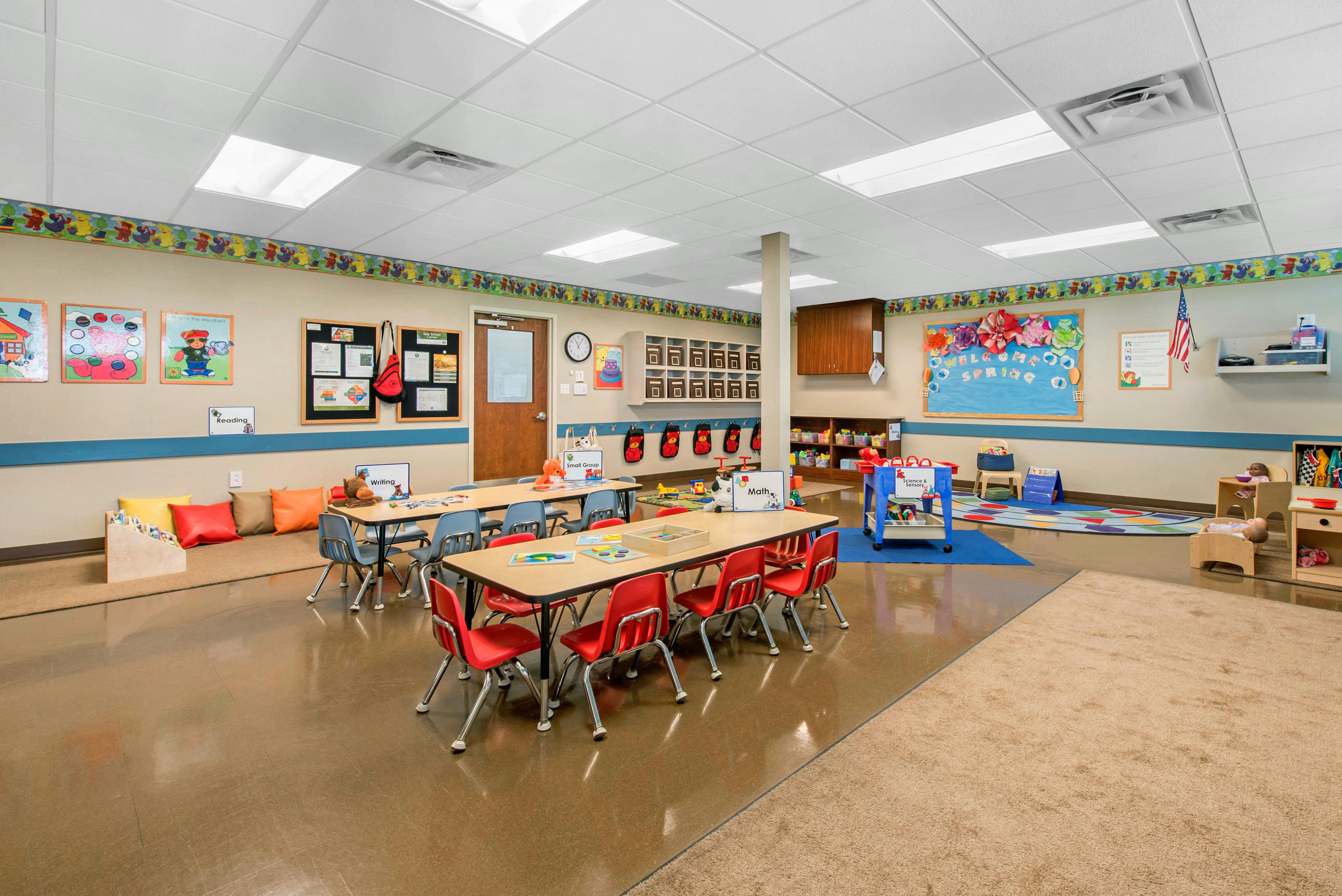 Classroom with small tables and chairs, activity centers, and decorative borders