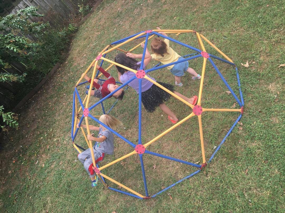 Children playing on a geodesic dome climber