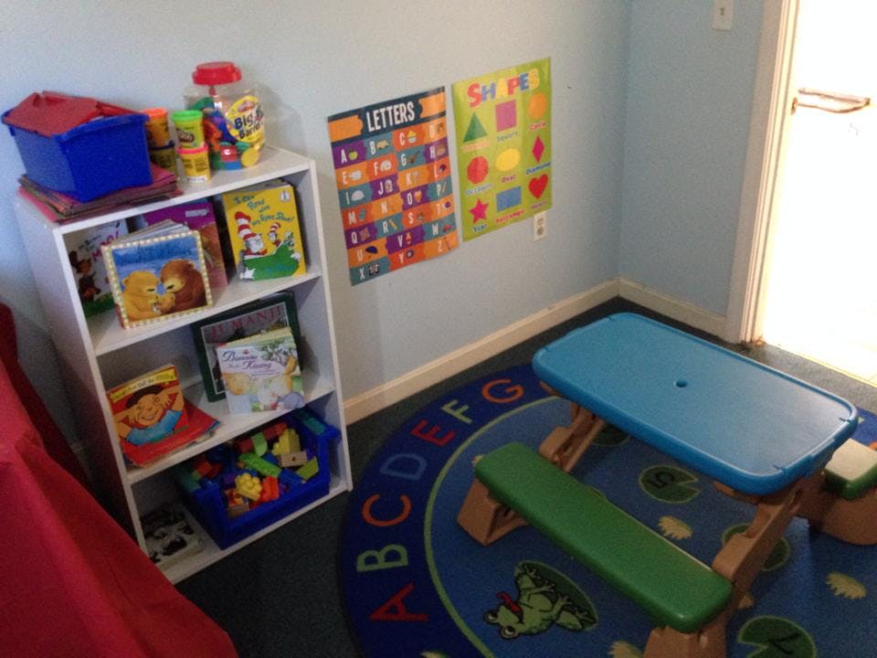 Children's play area with a bookshelf, alphabet rug, and small table