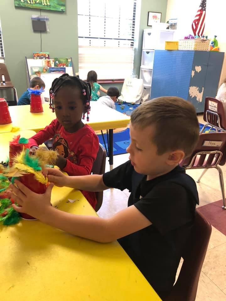 Two children at a yellow table doing crafts in-class crafts