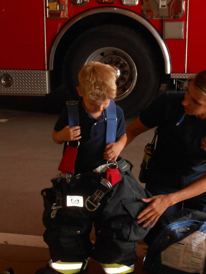 Child trying on firefighter gear with an adult