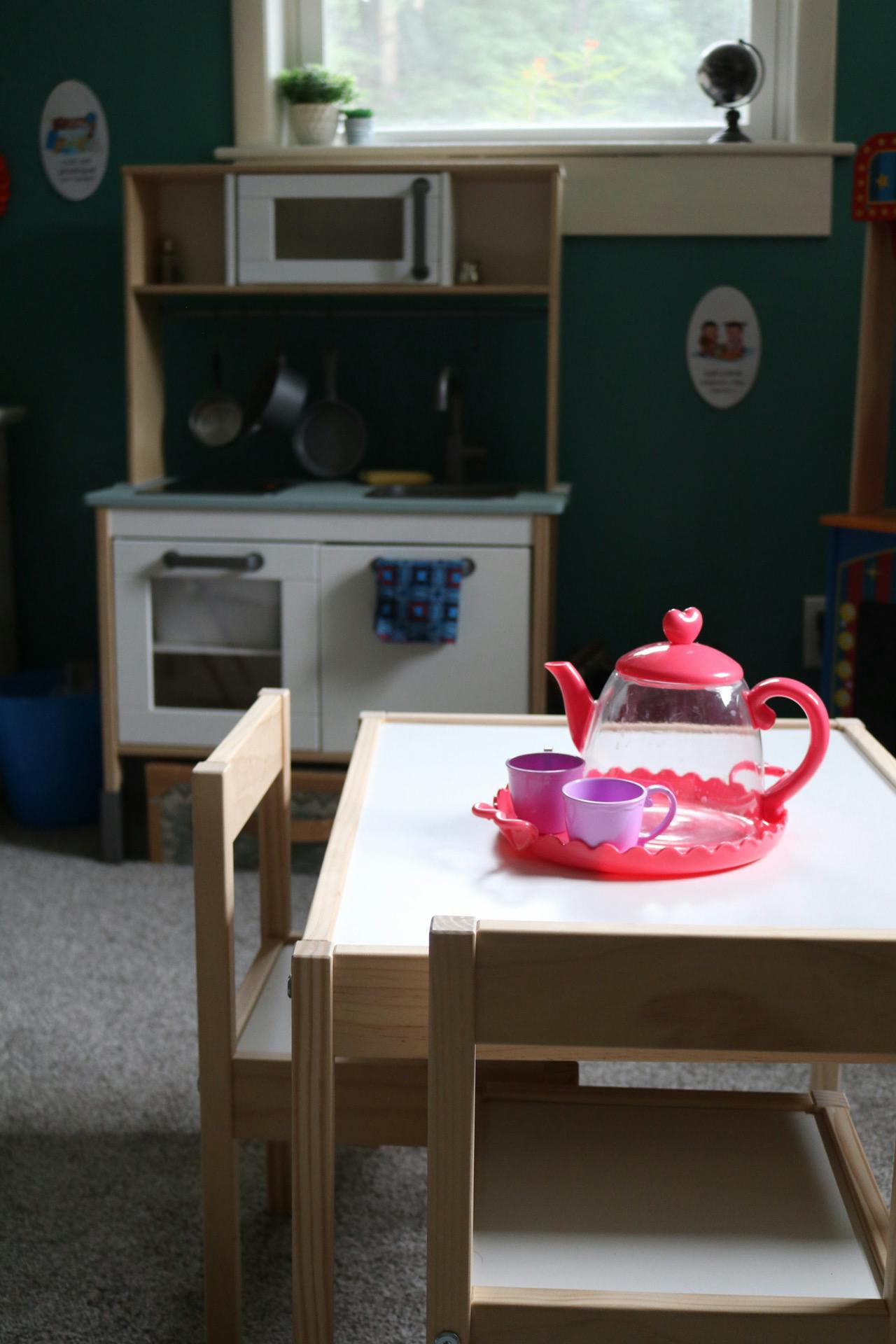 Toy tea set on a table with a play kitchen in the background