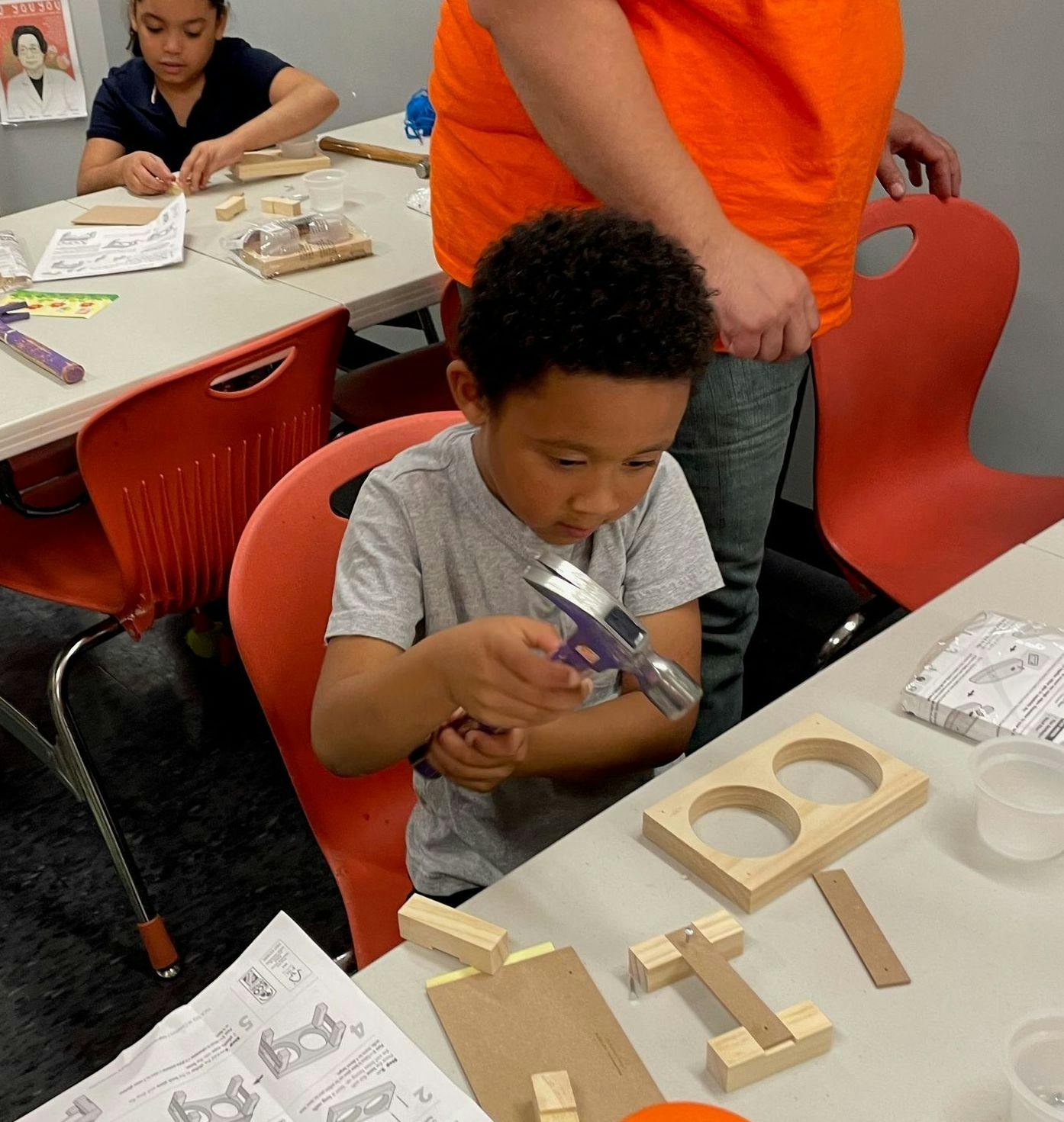 Child building a wooden project with a hammer at a table