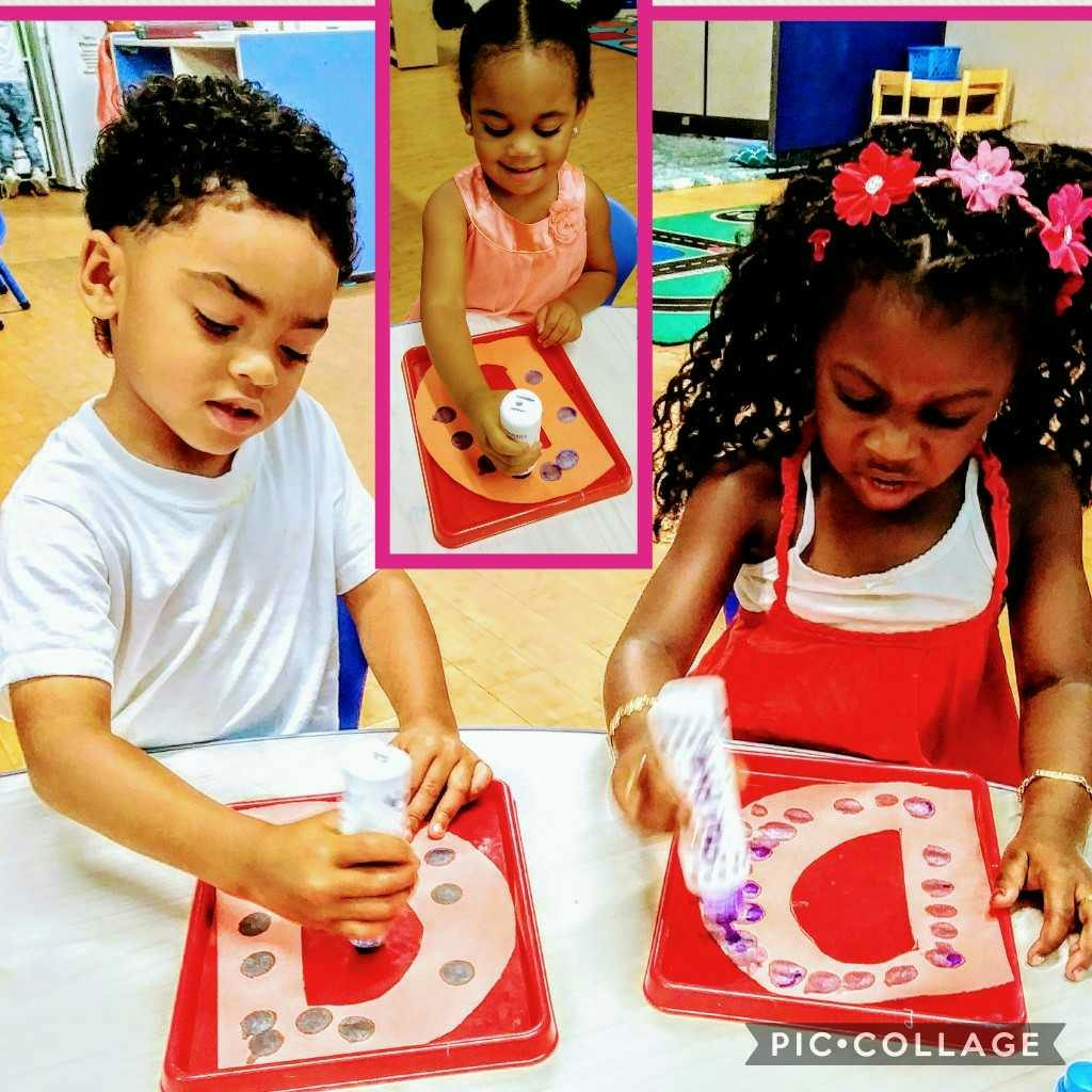 Three children doing crafts with letter D cutouts