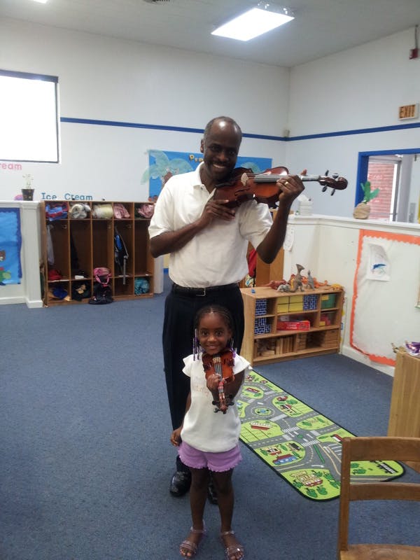 Person playing violin with a child standing in front
