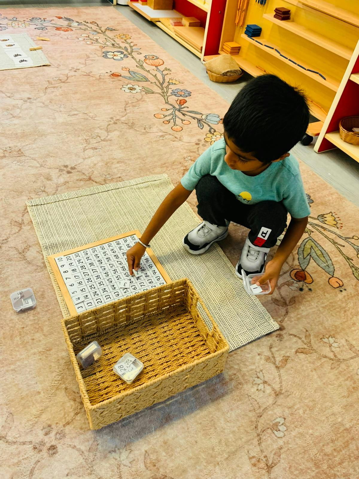 Child placing number tiles on a hundred board in a classroom