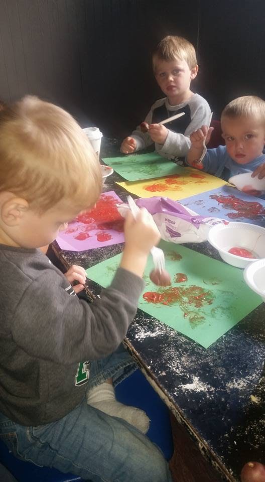 Three children doing an art activity with paint and paper