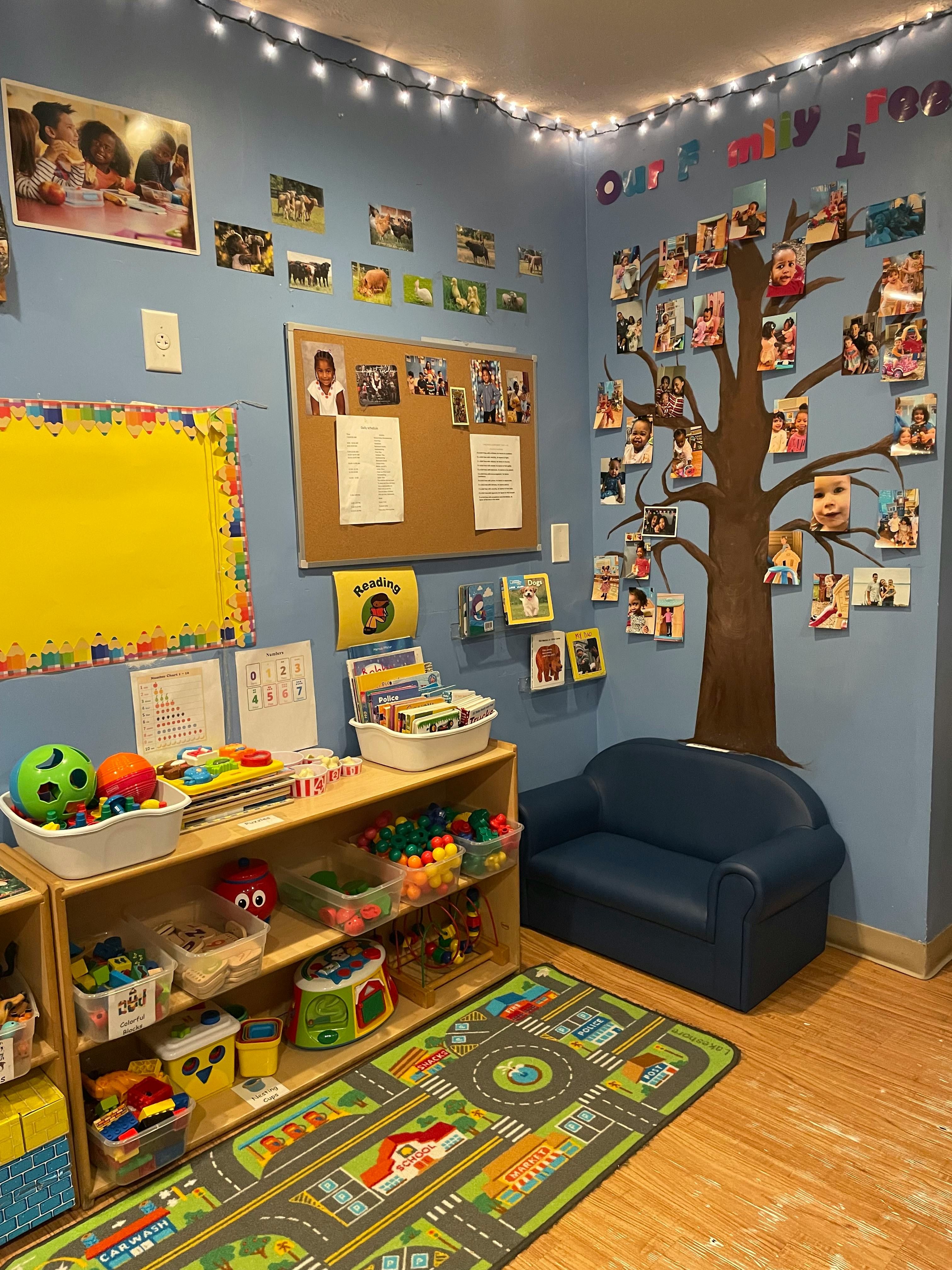 Classroom with a tree mural, bulletin board, toy shelves, and small couch