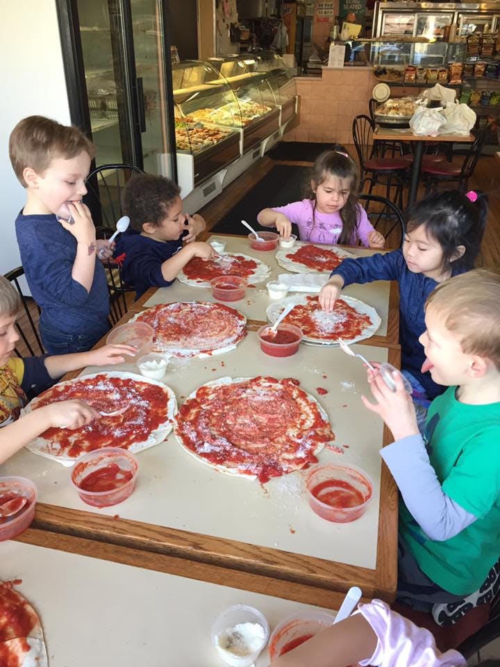 Children making pizzas at a table