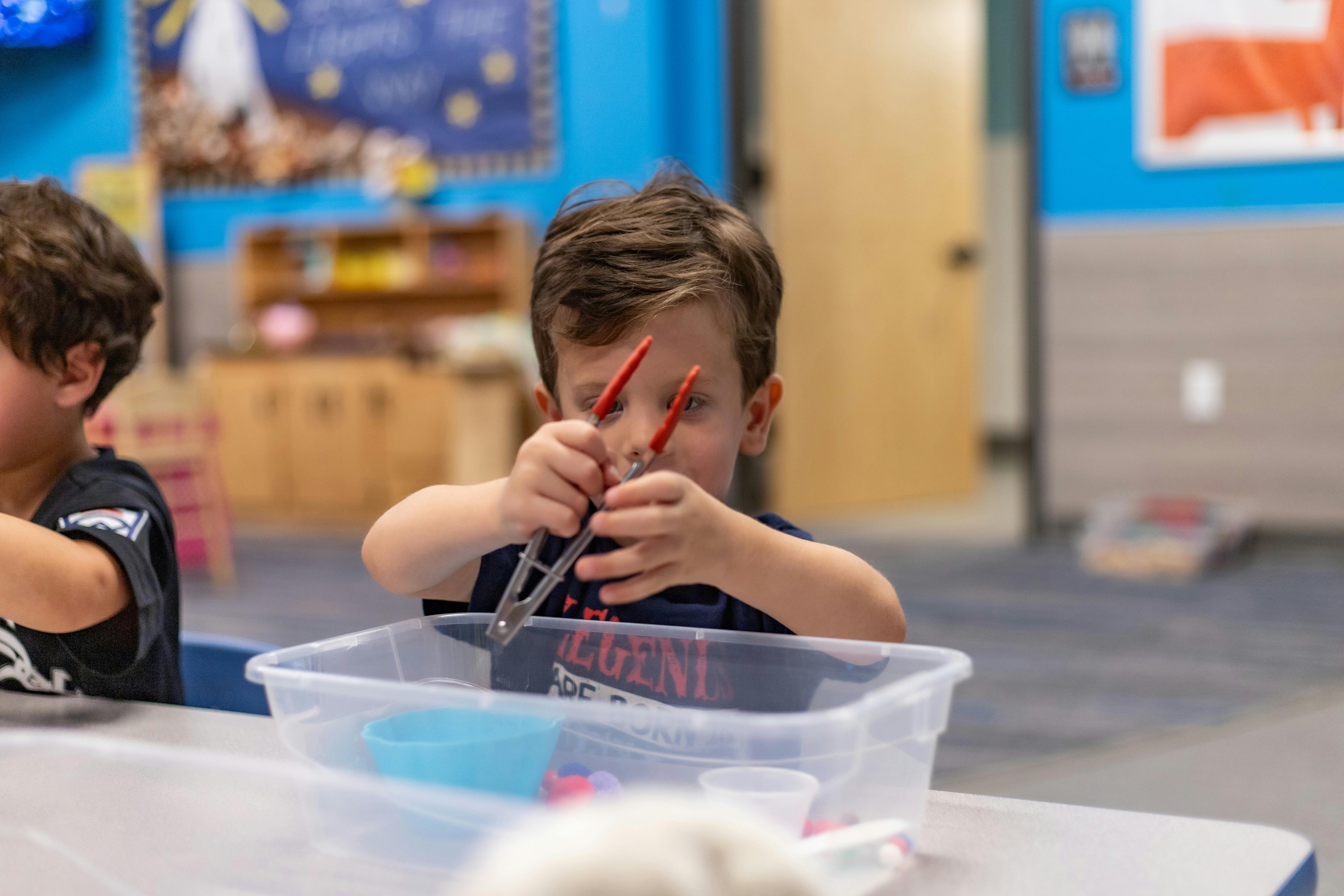 Child using tongs in a clear bin