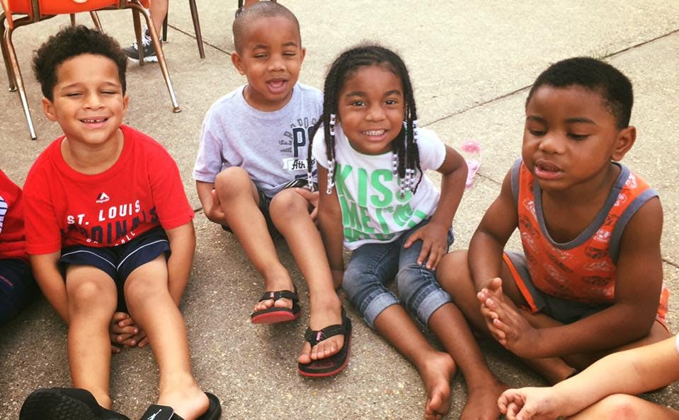 Four children sitting on the ground