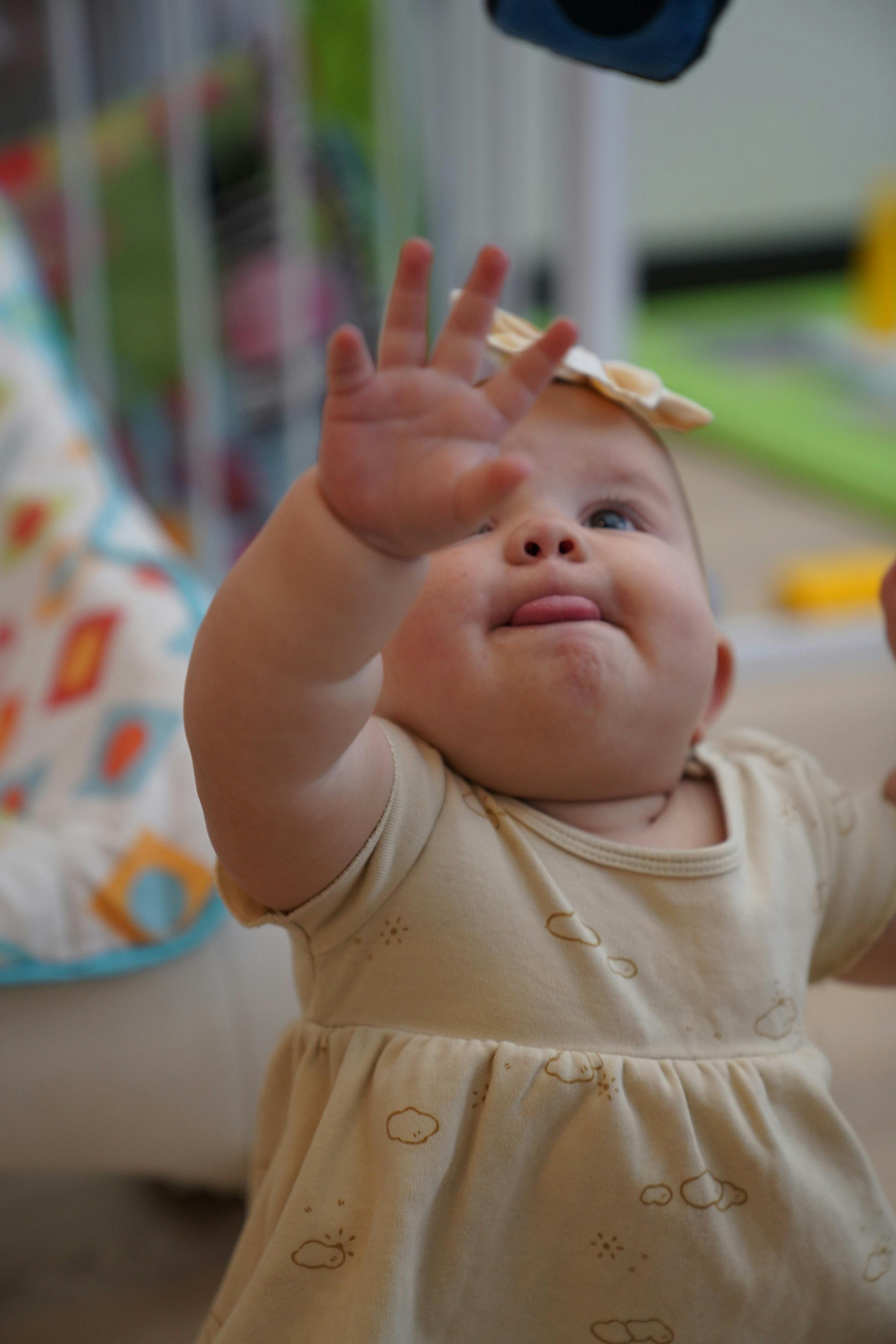 Child reaching up with one hand, tongue slightly out