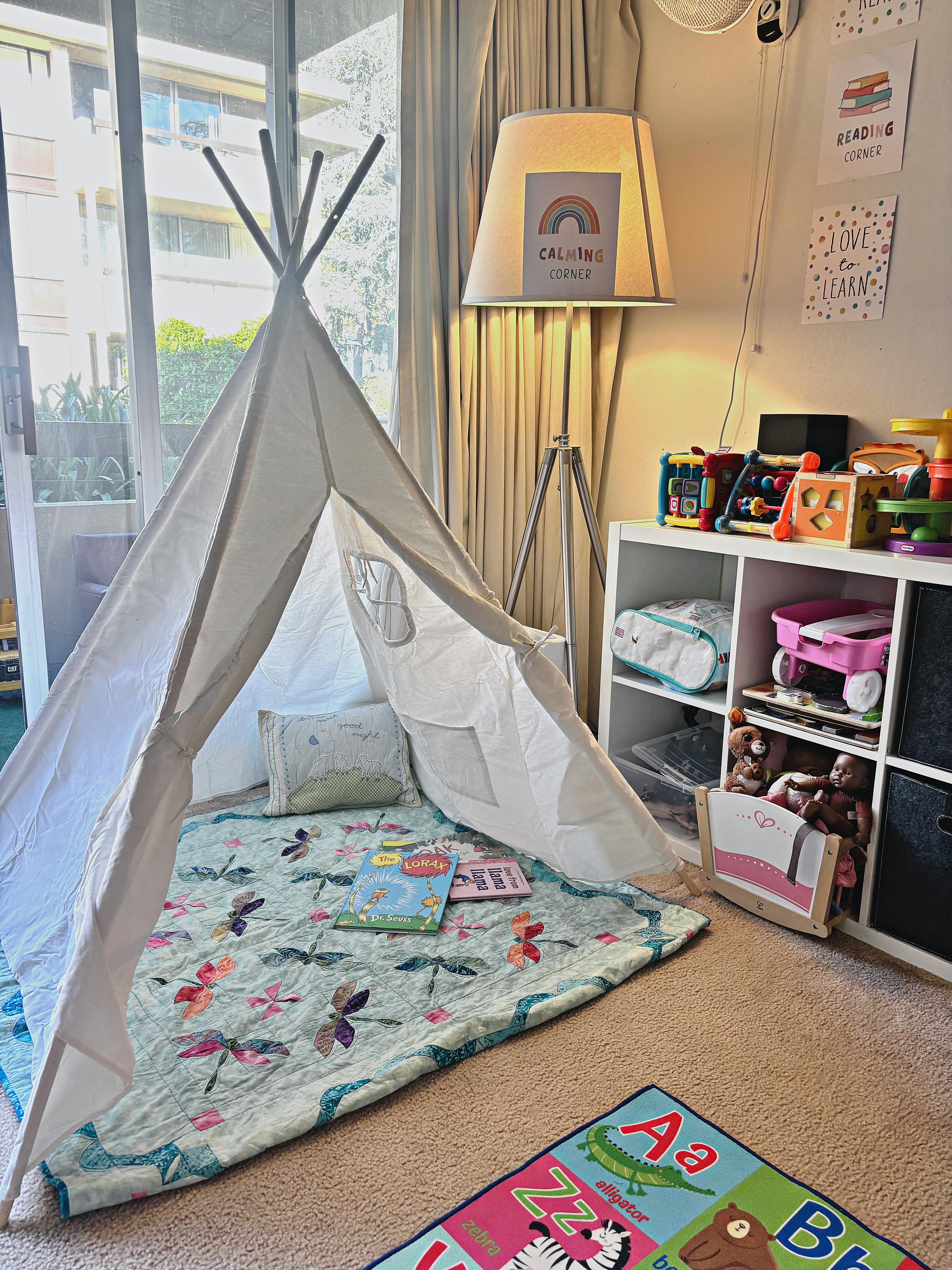 children's reading nook with a teepee tent and a calming corner sign on a lamp