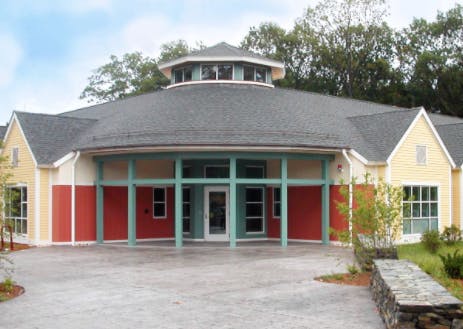 Building with red and yellow walls, a gray roof, and a teal-colored entrance