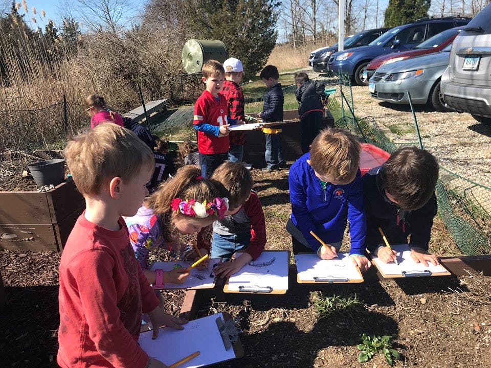 Children drawing on clipboards outdoors