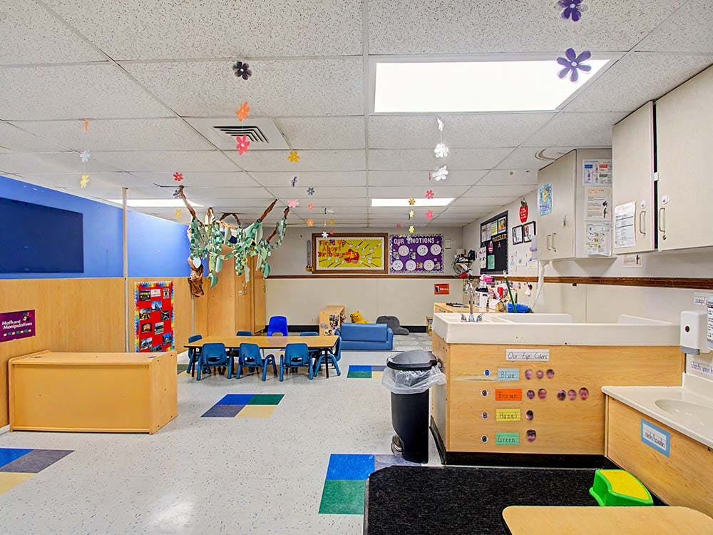 Classroom with tables, chairs, changing station, and decorations on the ceiling