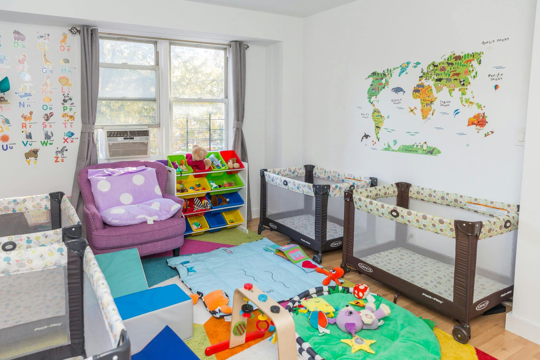 Nursery room with cribs, playmats, and a world map on the wall