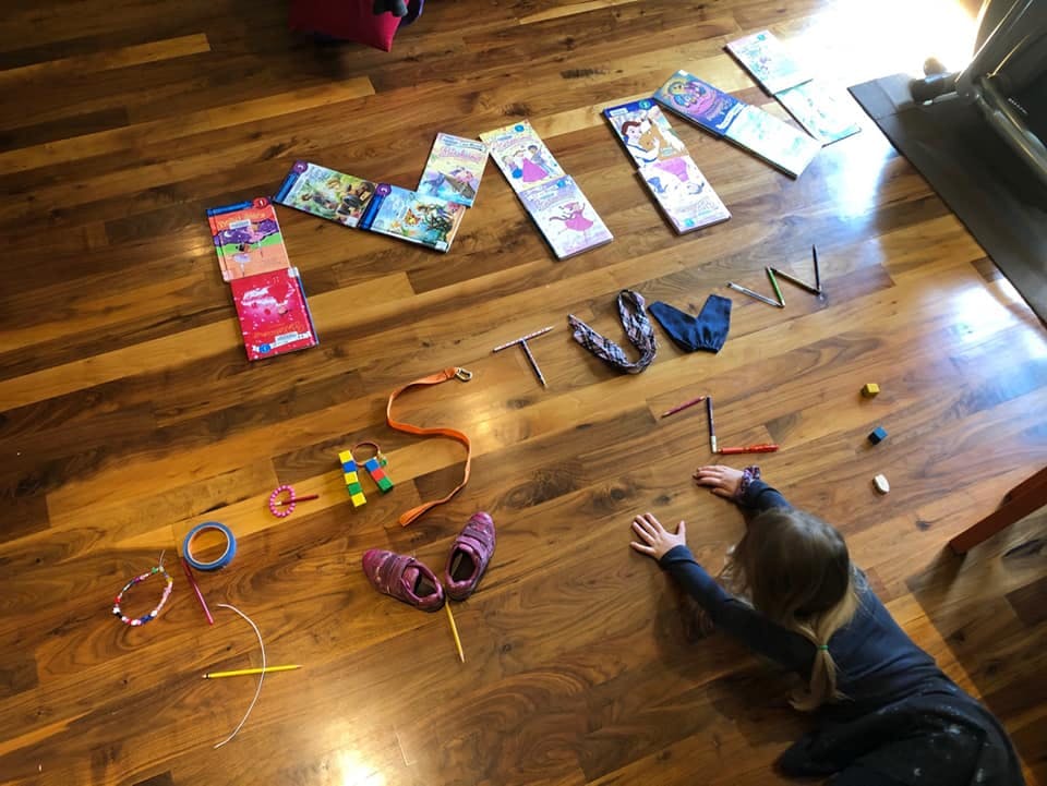 Child on floor arranging objects to spell out a name