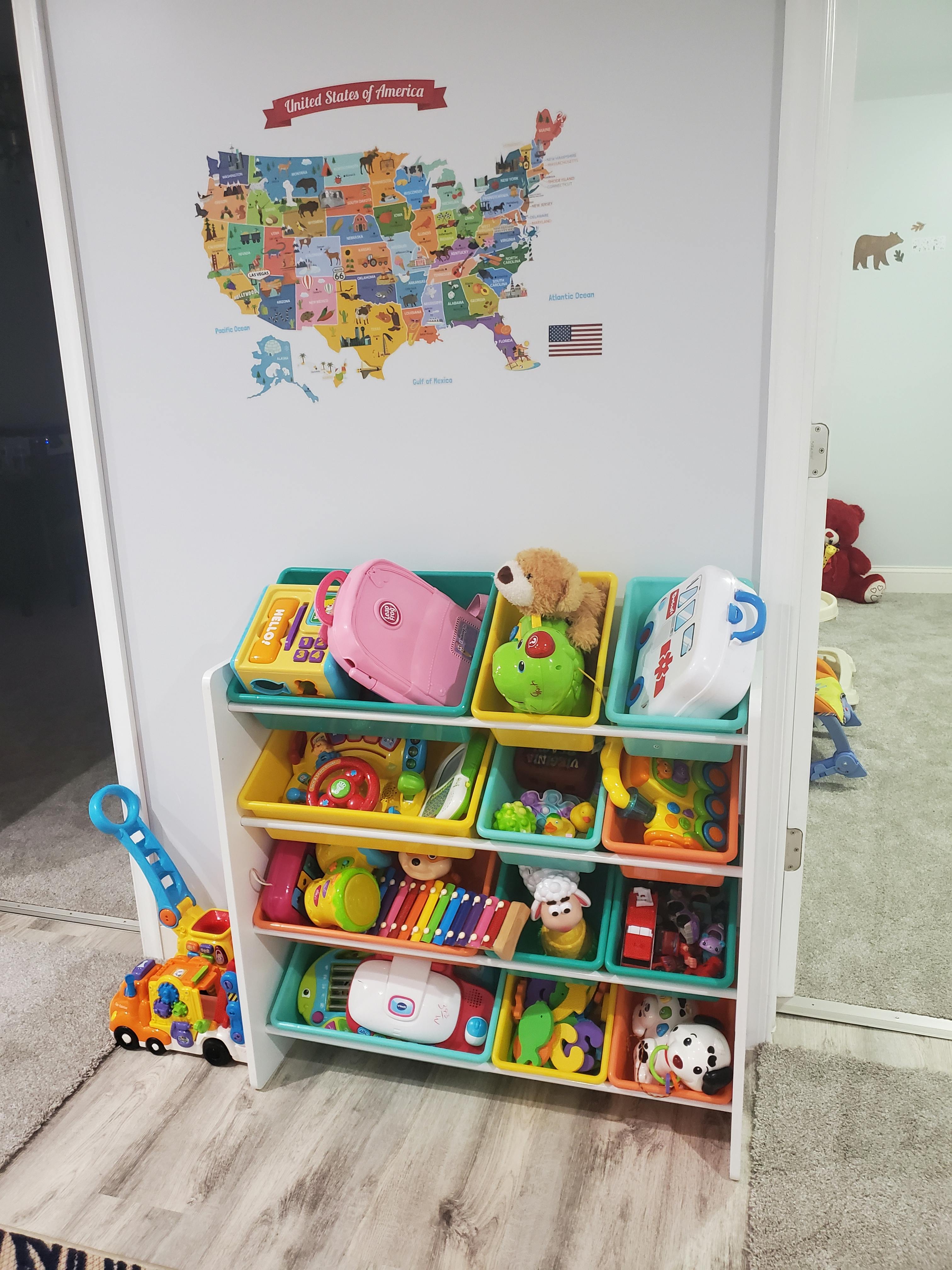 Toy organizer with colorful bins filled with various toys, US map on wall