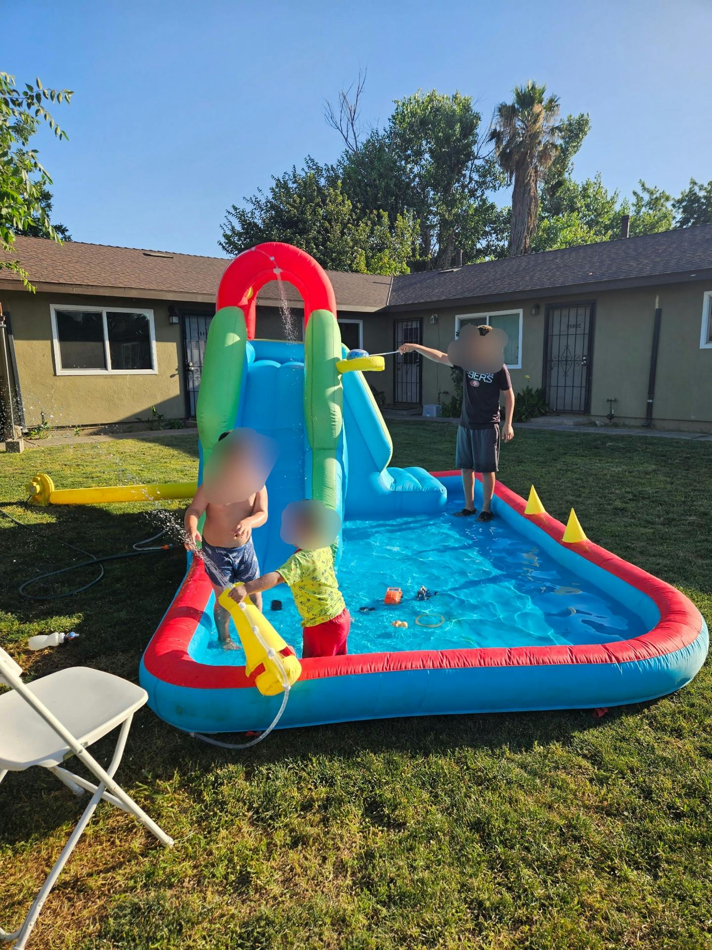 People playing in an inflatable water slide pool on a lawn