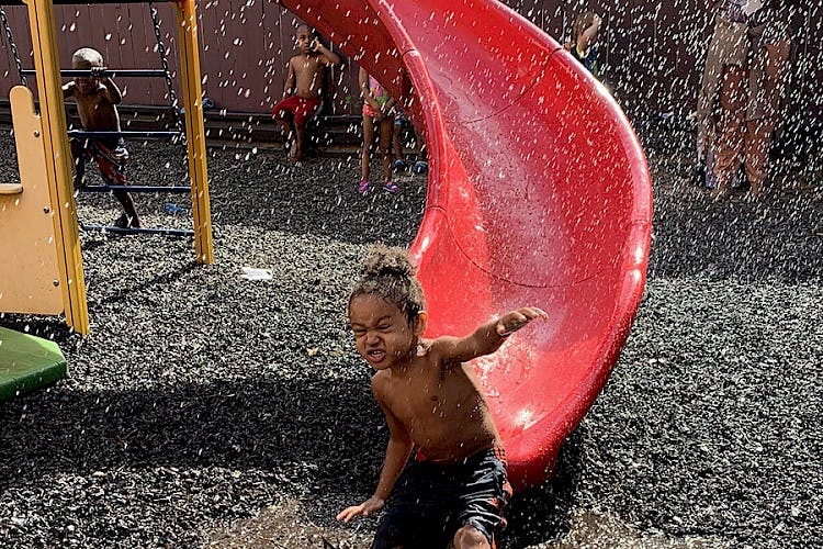 Child playing in water at the bottom of a red slide