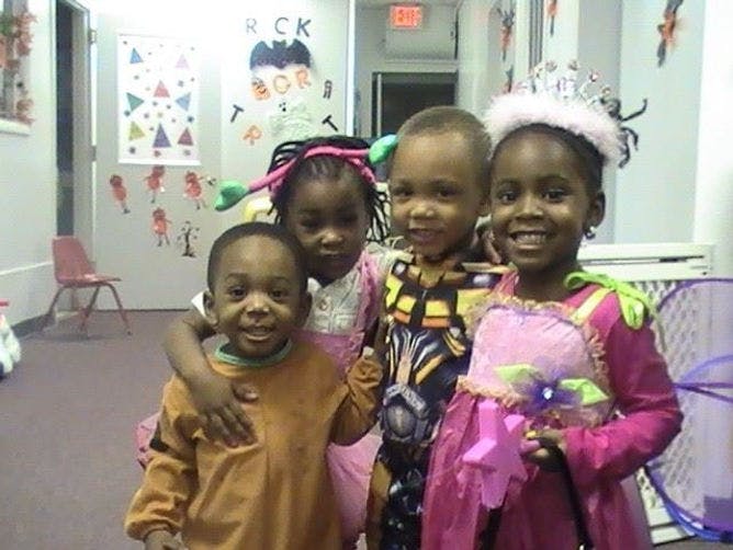 Four children in costumes posing together, one in a princess dress and tiara