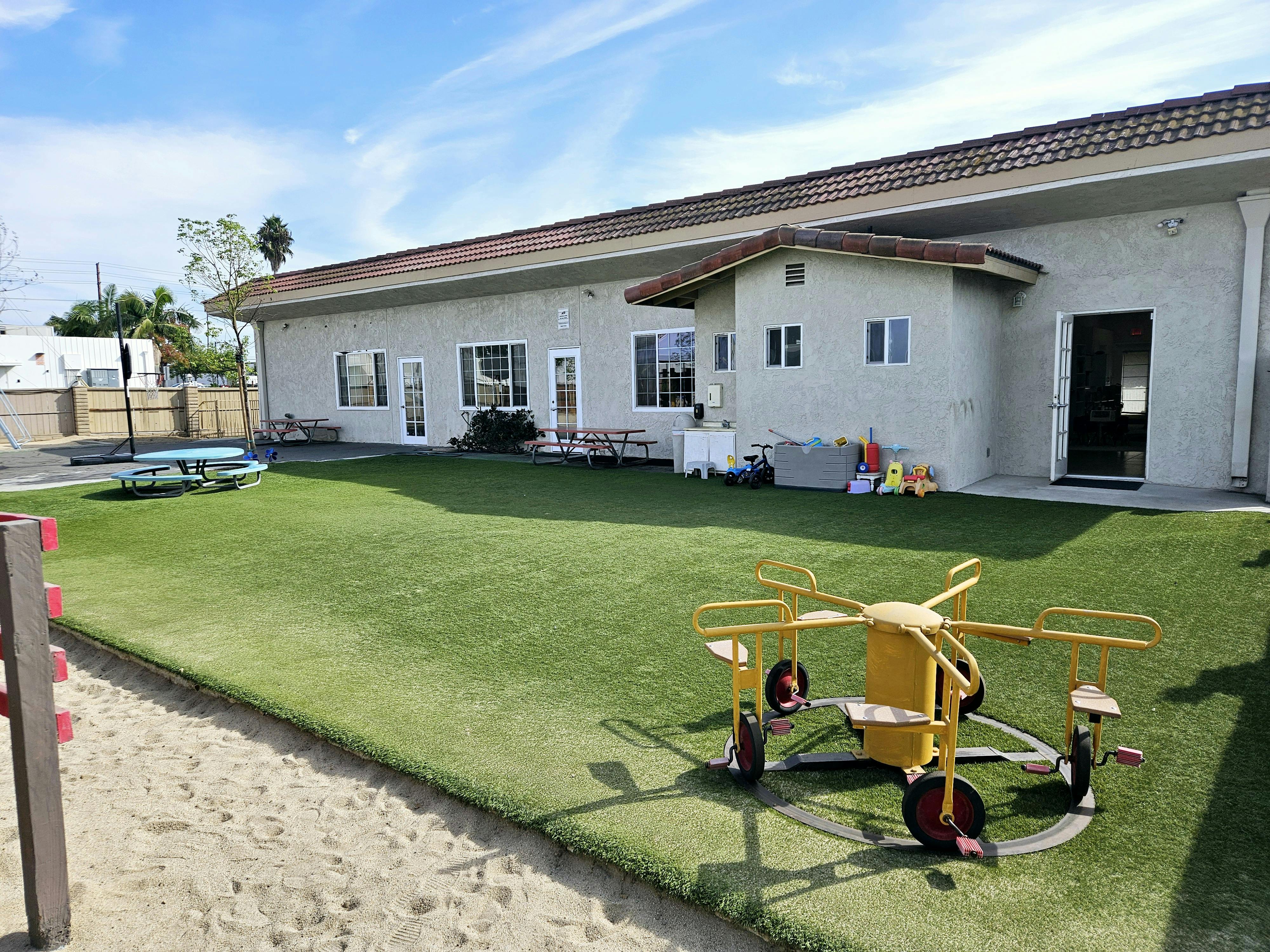 Playground with a yellow merry-go-round and a building in the background