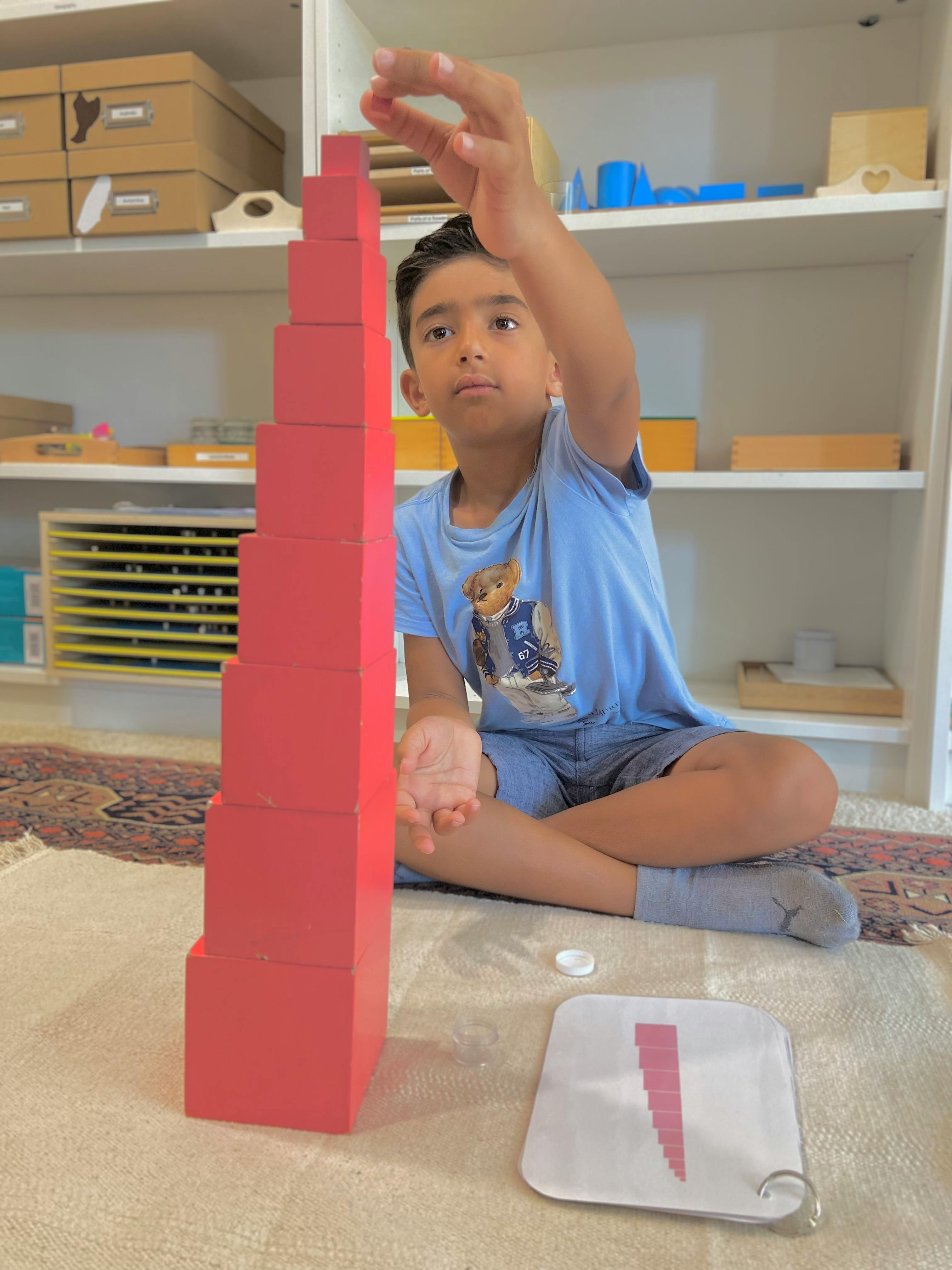 Child building a tower with red blocks