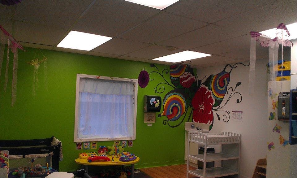Room with green walls, a window, and a colorful butterfly mural